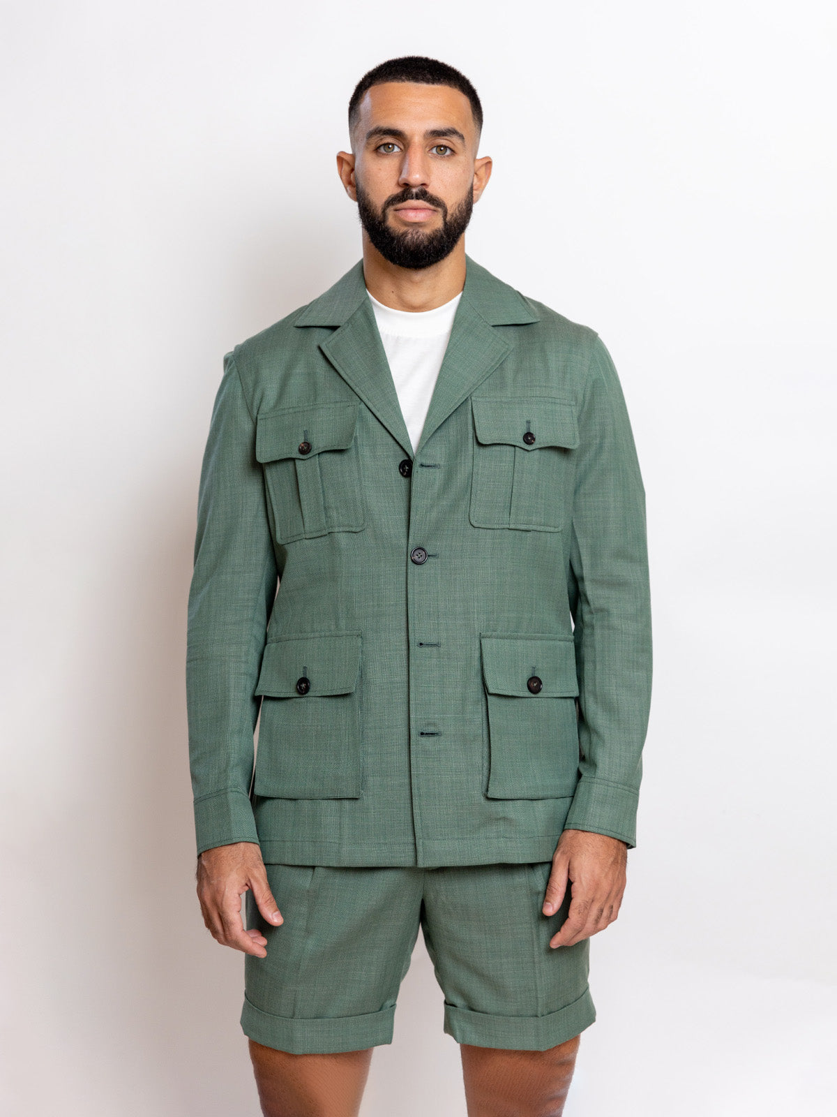 Man wearing a green jacket and shorts set on a white background