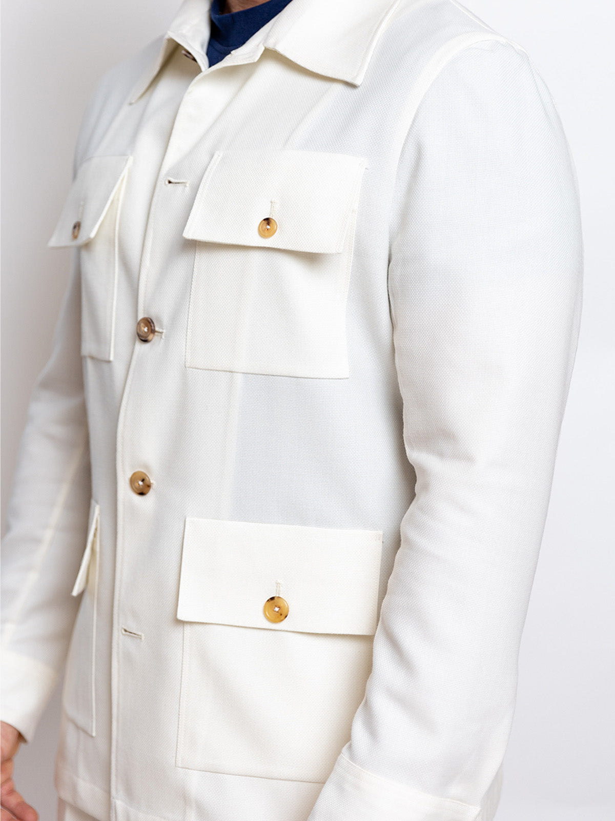 Close-up of a white coat with gold buttons on a plain background