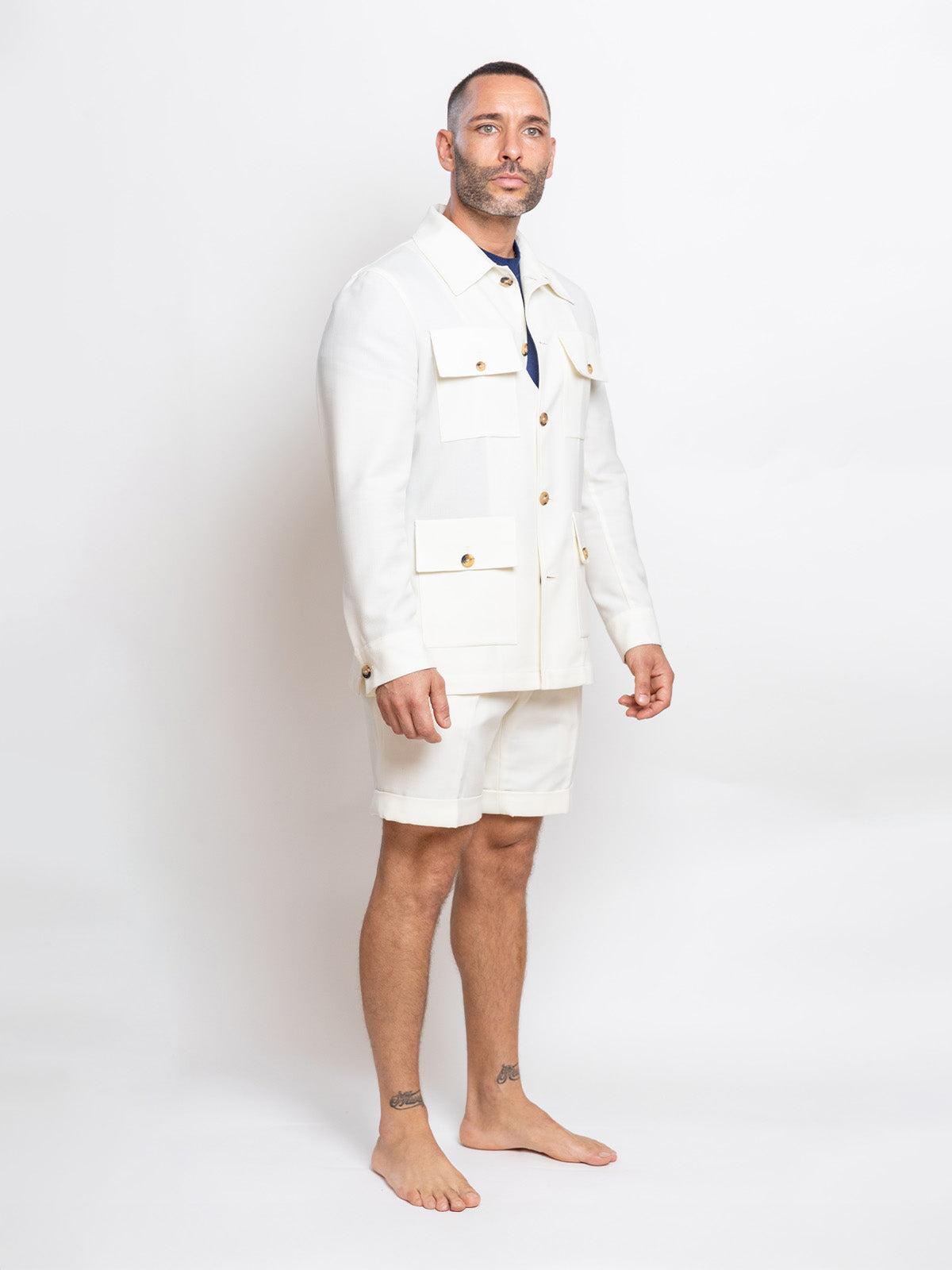 Man wearing a white blazer and shorts on a plain background